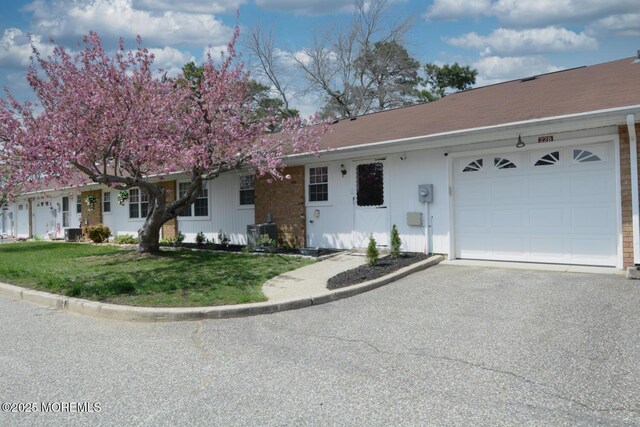 ranch-style house featuring a garage, central air condition unit, a front lawn, and aphalt driveway
