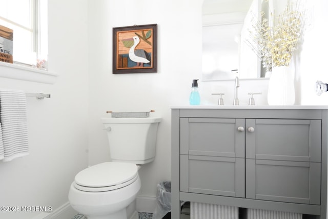 bathroom with plenty of natural light, vanity, toilet, and baseboards