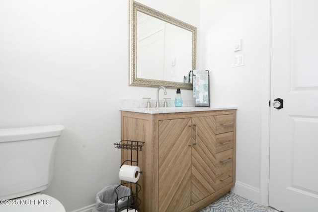 half bathroom featuring vanity, toilet, and baseboards