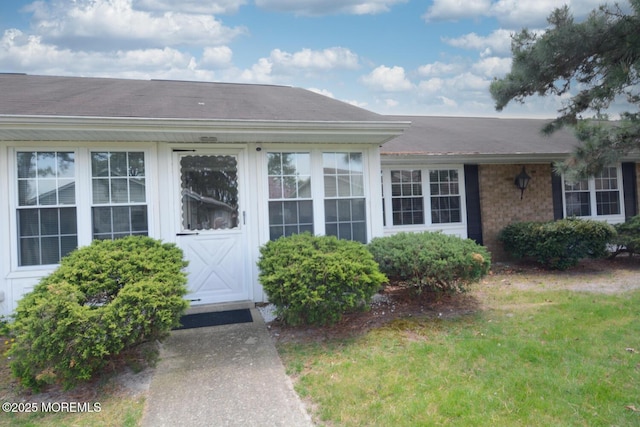 doorway to property with a yard and brick siding