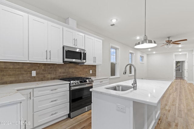 322 Lincoln Ave, Seaside Heights, NJ 08751 - kitchen featuring a sink, tasteful backsplash, white cabinetry, an island with sink, and appliances with stainless steel finishes