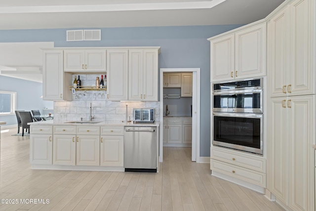 107 Bay Shore Dr, Toms River, NJ 08753 - kitchen with backsplash, visible vents, a sink, light wood finished floors, and stainless steel appliances