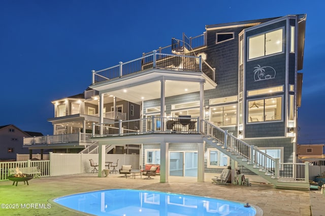 107 Bay Shore Dr, Toms River, NJ 08753 - back of house at night featuring fence, a balcony, a fenced in pool, a patio area, and stairway