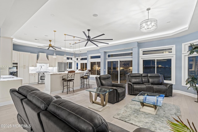 107 Bay Shore Dr, Toms River, NJ 08753 - living room featuring a tray ceiling, ceiling fan with notable chandelier, and light wood-type flooring