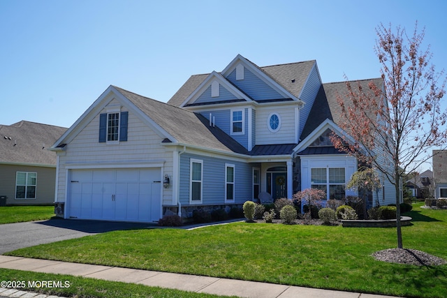 view of front of house with a front lawn, driveway, stone siding, an attached garage, and roof with shingles