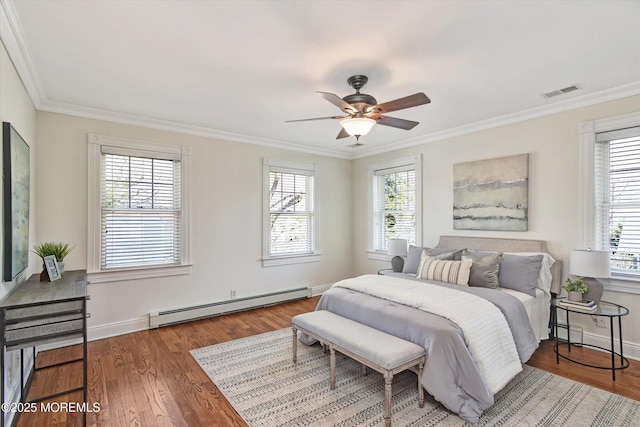 bedroom with wood finished floors, baseboard heating, visible vents, and multiple windows