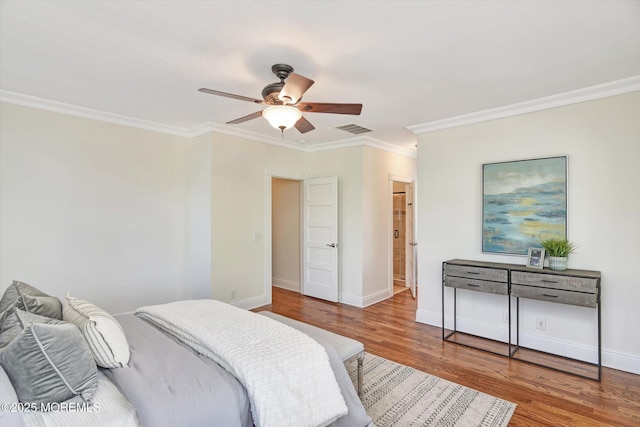 bedroom featuring visible vents, baseboards, wood finished floors, and ornamental molding