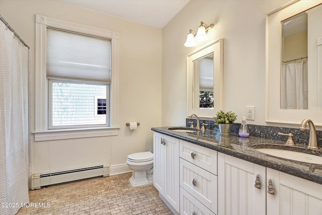bathroom featuring double vanity, a sink, a baseboard radiator, and toilet