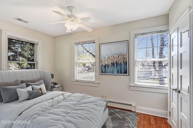 bedroom with visible vents, dark wood-style flooring, baseboards, baseboard heating, and ceiling fan
