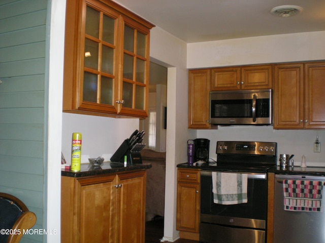 24 Dartmouth St Unit 61, Whiting, NJ 08759 - kitchen with brown cabinetry, appliances with stainless steel finishes, visible vents, and glass insert cabinets