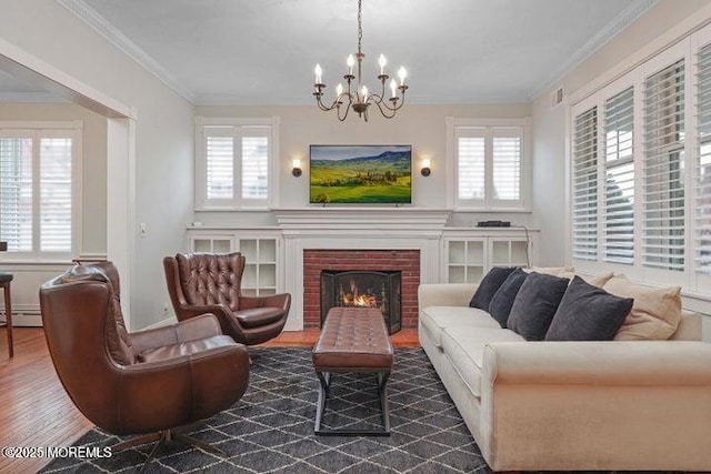 living room with a baseboard heating unit, an inviting chandelier, dark wood-type flooring, and a healthy amount of sunlight