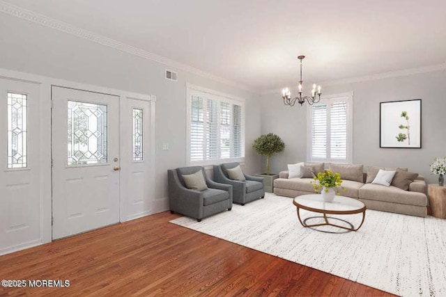 living area featuring wood finished floors, a chandelier, and ornamental molding