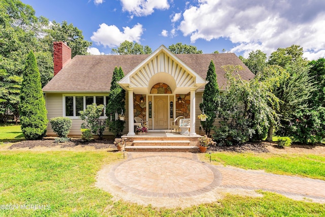 view of front of home featuring covered porch, a shingled roof, a chimney, and stone siding