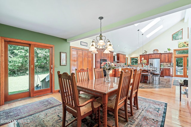 dining room with light wood-style floors, a chandelier, a skylight, and high vaulted ceiling