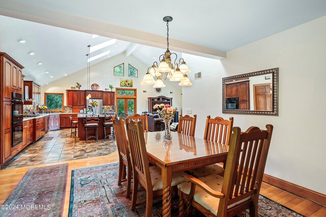 dining area featuring an inviting chandelier, beam ceiling, visible vents, and light wood-style flooring