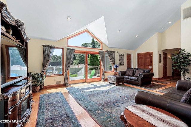 living area featuring baseboards, wood finished floors, visible vents, and high vaulted ceiling
