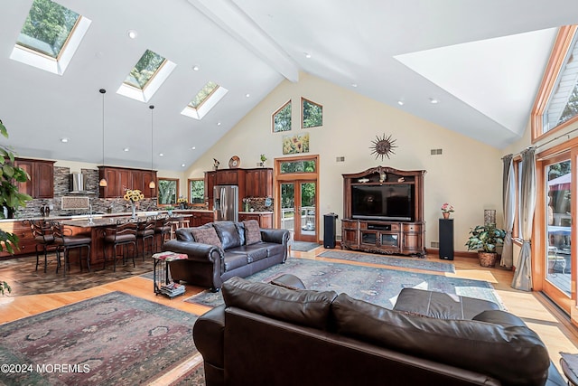 living area with light wood-type flooring, a wealth of natural light, high vaulted ceiling, and a skylight