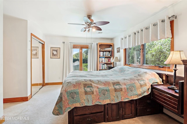 bedroom with a baseboard heating unit, light colored carpet, ceiling fan, baseboards, and access to exterior