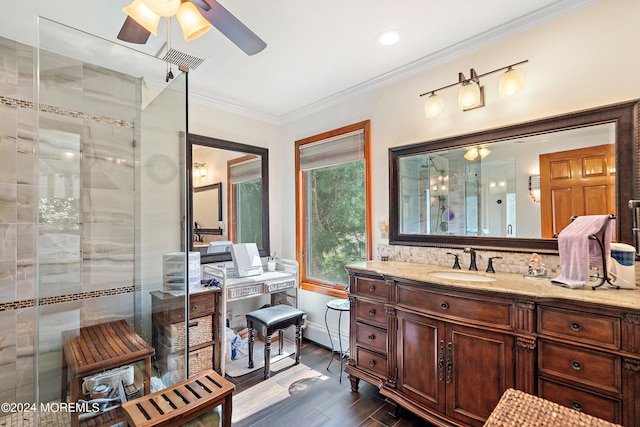 bathroom featuring ornamental molding, ceiling fan, tiled shower, vanity, and wood finished floors