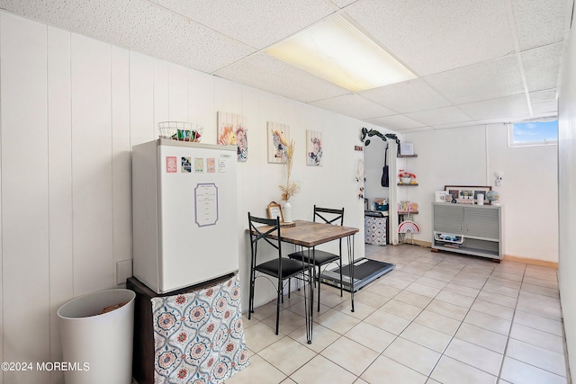dining room with a drop ceiling and light tile patterned flooring