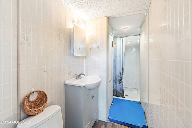 bathroom featuring a stall shower, tile walls, toilet, vanity, and wood finished floors