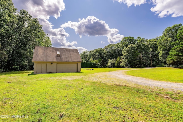view of yard featuring an outdoor structure, driveway, and a detached garage