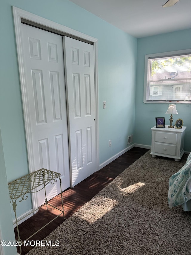 bedroom with baseboards, a closet, wood finished floors, and visible vents