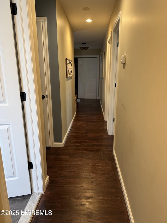 hall with dark wood-type flooring, recessed lighting, and baseboards