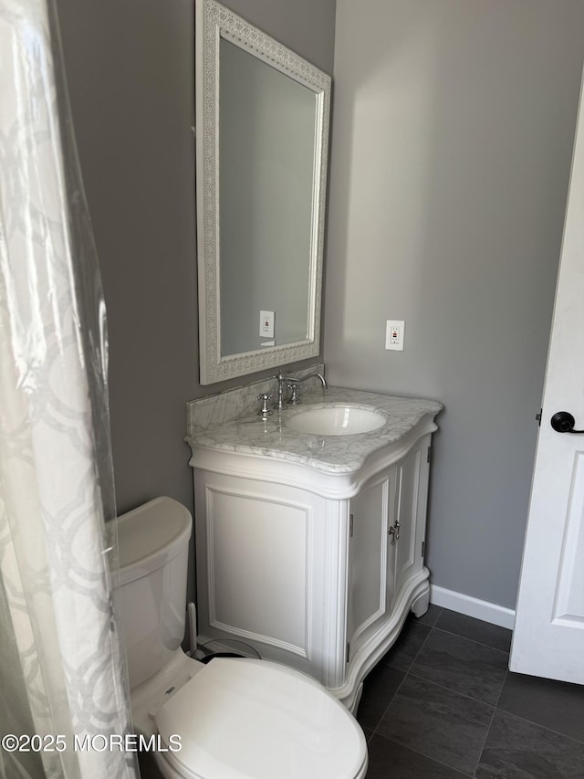bathroom featuring vanity, baseboards, and toilet