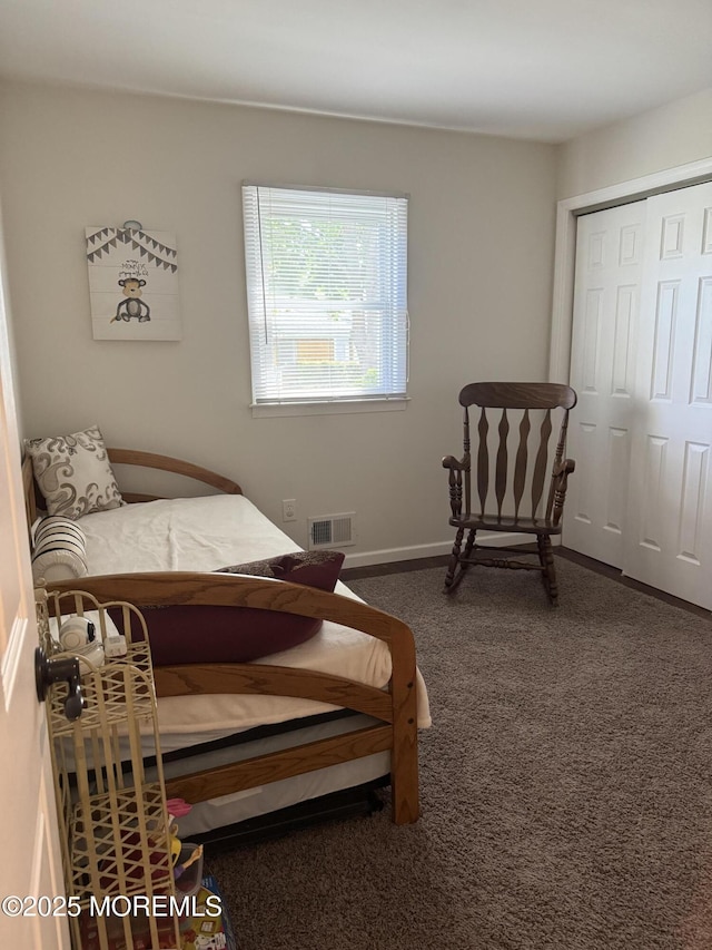 bedroom with baseboards, a closet, dark colored carpet, and visible vents