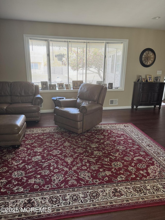 living room with dark wood-style flooring, visible vents, and a healthy amount of sunlight