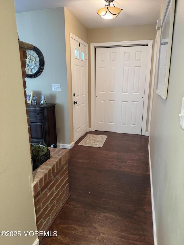 doorway featuring dark wood-style flooring and baseboards
