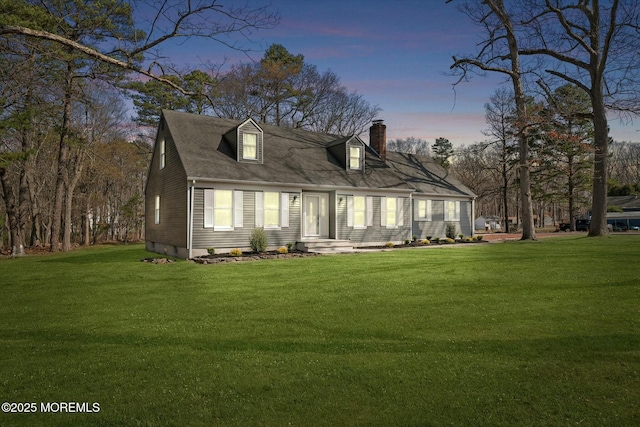 back of house at dusk with a lawn and a chimney