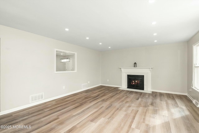 unfurnished living room with recessed lighting, wood finished floors, visible vents, and a fireplace with flush hearth