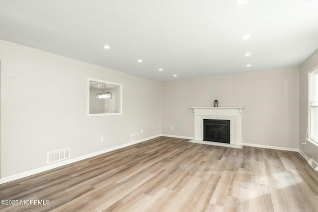 unfurnished living room with a fireplace with flush hearth, wood finished floors, visible vents, and recessed lighting