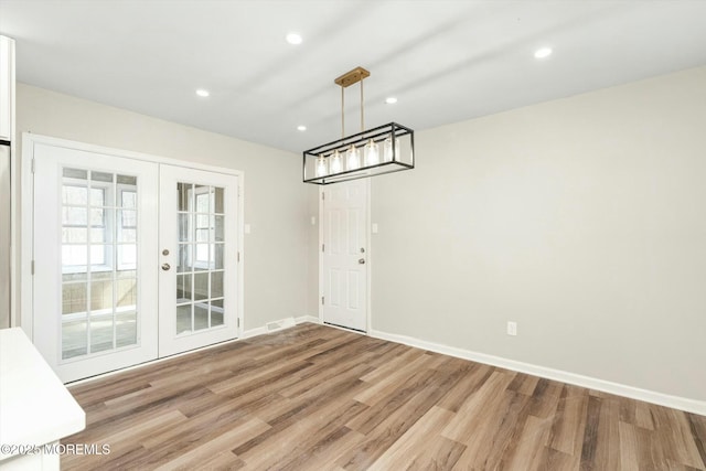 unfurnished dining area featuring recessed lighting, baseboards, french doors, and light wood-style flooring