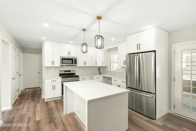 kitchen with light countertops, a wealth of natural light, a center island, decorative backsplash, and appliances with stainless steel finishes