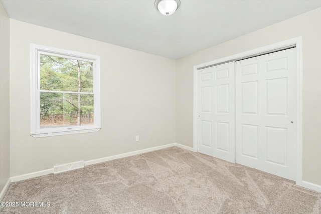 unfurnished bedroom with baseboards, visible vents, carpet floors, and a closet