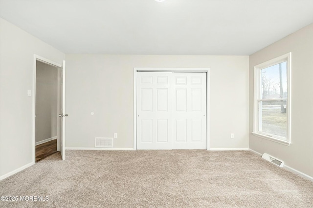unfurnished bedroom featuring baseboards, visible vents, carpet, and a closet