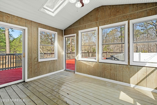 unfurnished sunroom with ceiling fan, a healthy amount of sunlight, and a skylight