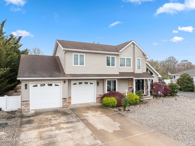 view of front of house with driveway, roof with shingles, stone siding, and fence