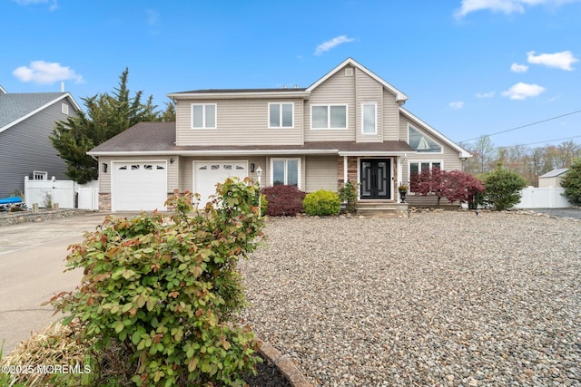 traditional home with driveway, a garage, a shingled roof, and fence