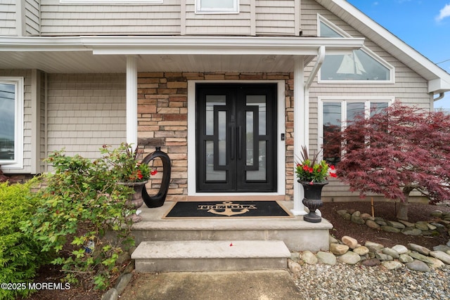 entrance to property with a porch and stone siding