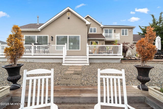 back of house with a deck and a shingled roof