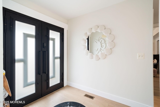 foyer entrance with light wood finished floors, french doors, visible vents, and baseboards
