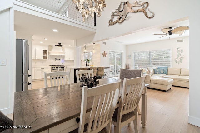 dining space featuring recessed lighting, light wood finished floors, visible vents, and ceiling fan with notable chandelier