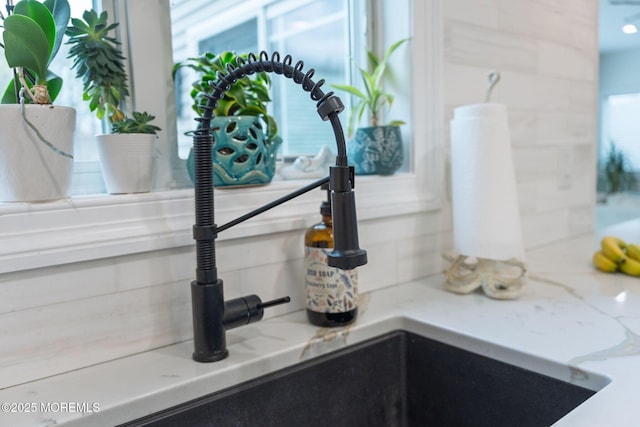 interior details with light stone countertops, a sink, and tasteful backsplash