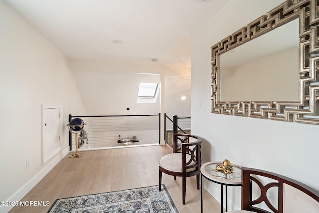 sitting room featuring an upstairs landing, a skylight, wood finished floors, and baseboards