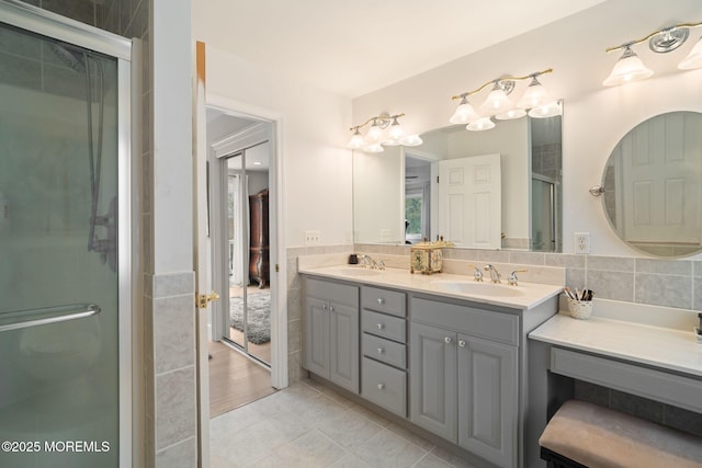 bathroom featuring tile walls, a stall shower, double vanity, and a sink