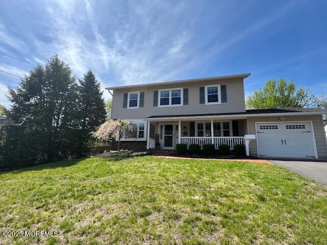 view of front of property with driveway, covered porch, a front yard, and a garage
